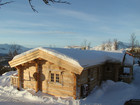 Fasade av vakre Bygdin laftehytte omgitt av snø (5)